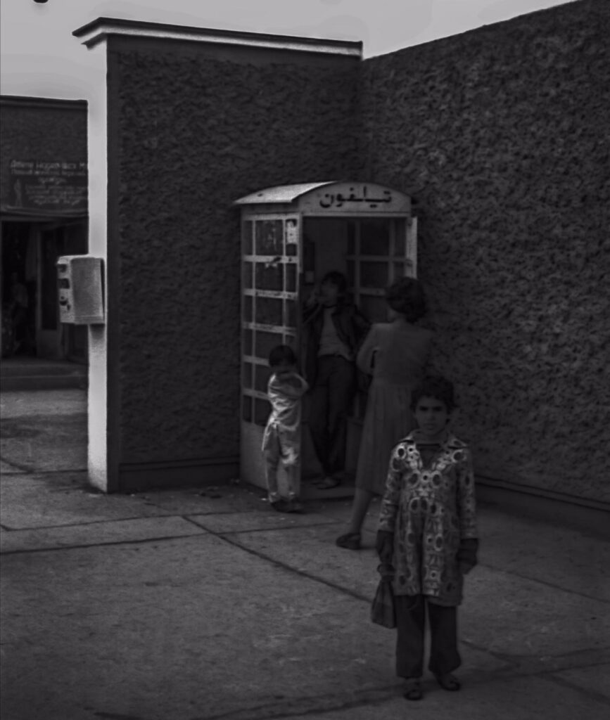 A woman waiting in line for a public phone.